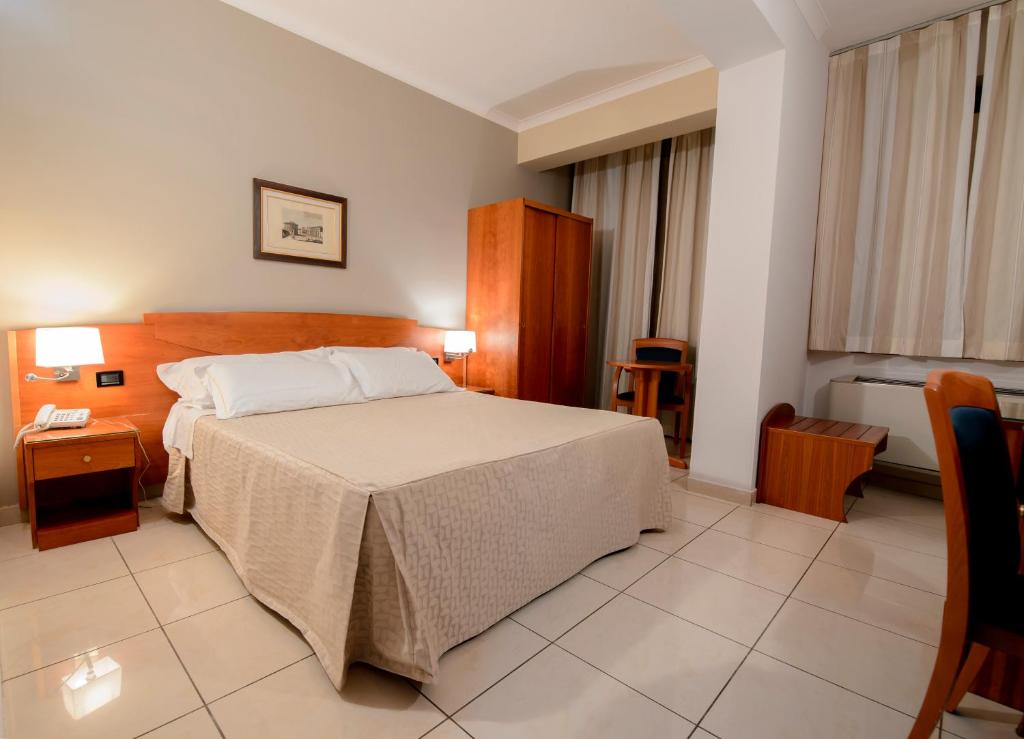 ノーラにあるHotel dei Plataniのベッドルーム1室(ベッド1台、テーブル、椅子付)