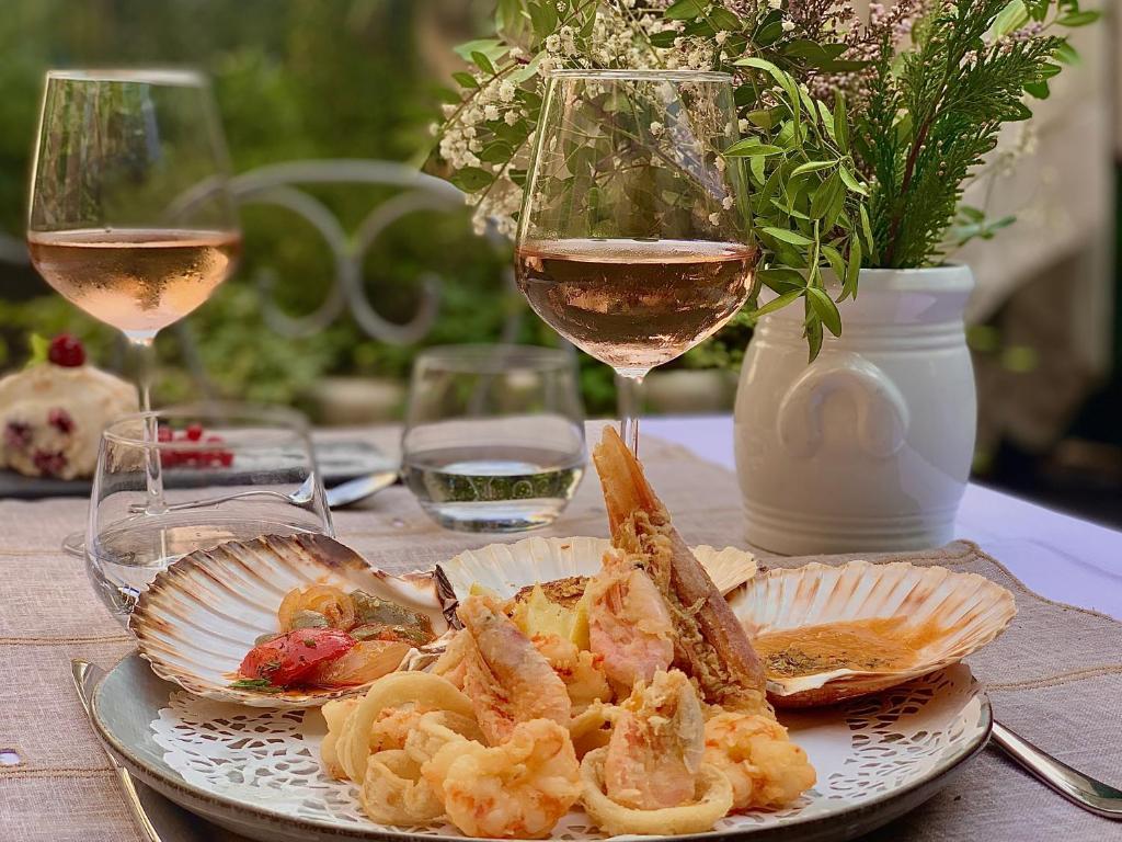 a table with a plate of food and two glasses of wine at Hôtel restaurant Oasis in Nice