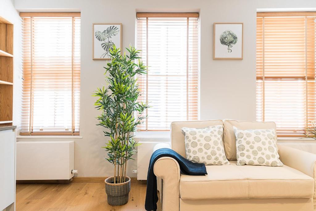 a living room with a couch and a plant at Stylish Stays by Russel Square in London