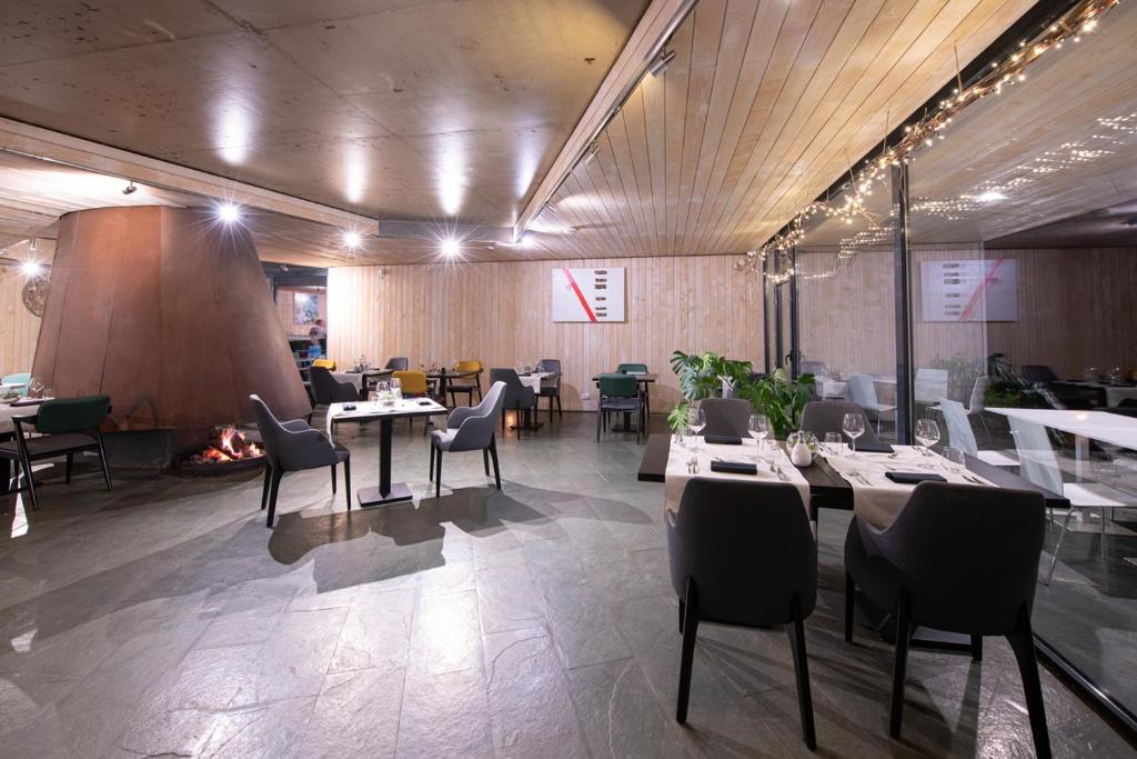 a restaurant with tables and chairs and a fireplace at Pensiunea Atra Doftana in Teşila