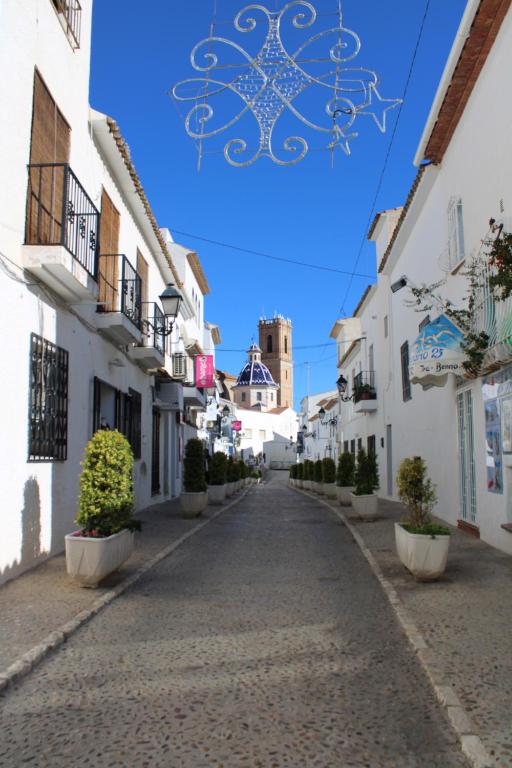 an alley with white buildings and potted plants at Hostal Fornet Altea in Altea