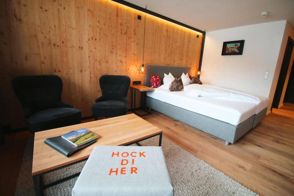 a bedroom with a bed and two chairs and a table at Berghotel Basur - Das Schihotel am Arlberg in Flirsch