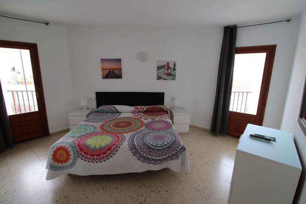a bedroom with a bed and a table and two windows at Hostal Fornet Altea in Altea
