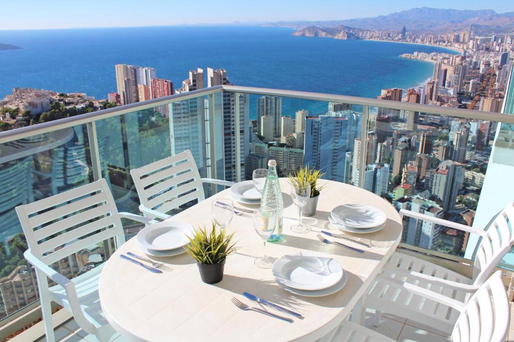 a white table with chairs and a view of the city at Benidorm High rise apartments - Sea Views - Torre Lugano in Benidorm