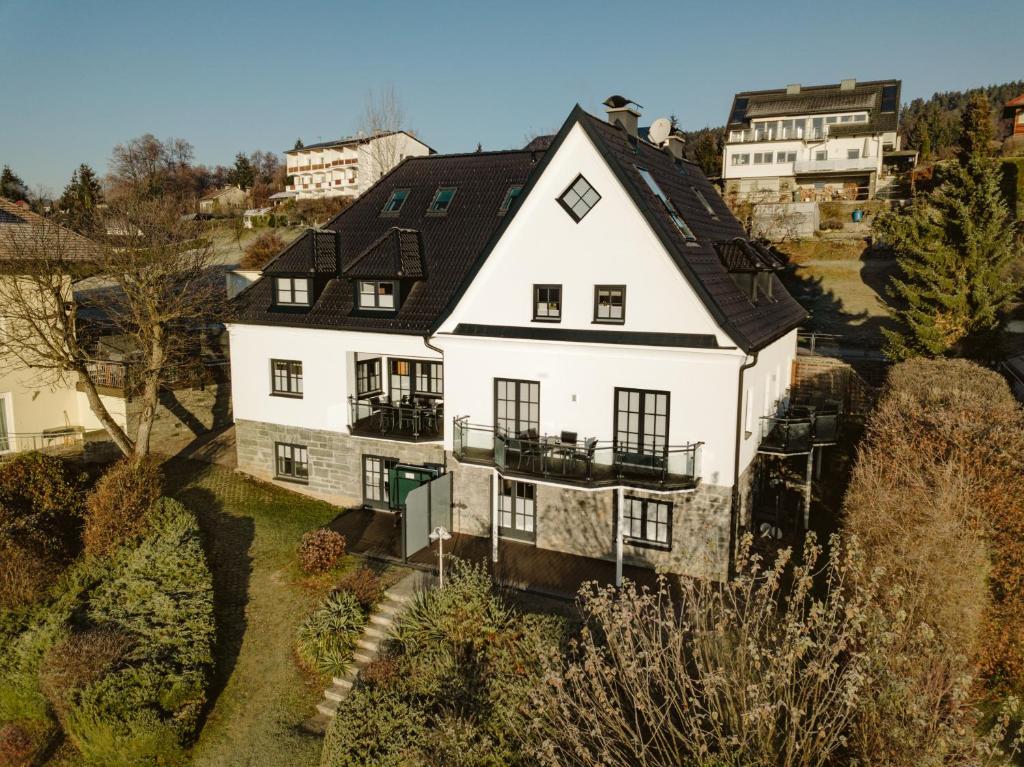 eine Luftansicht eines weißen Hauses mit schwarzem Dach in der Unterkunft Haus Aussicht - Ferienwohnungen Velden in Velden am Wörthersee