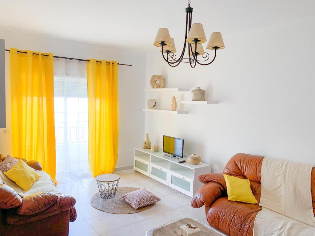 a living room with a couch and a television at Apartamento T2 Carvoeiro-Lagoa preços acessíveis in Lagoa
