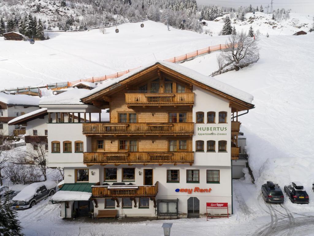 ein großes Holzgebäude im Schnee in der Unterkunft Hubertushof Ferienwohnungen in Gerlos