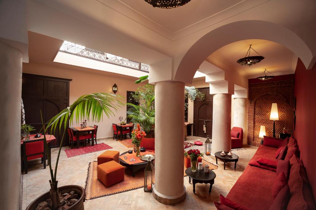 ein großes Wohnzimmer mit roten Sofas und Tischen in der Unterkunft Riad Boussa in Marrakesch