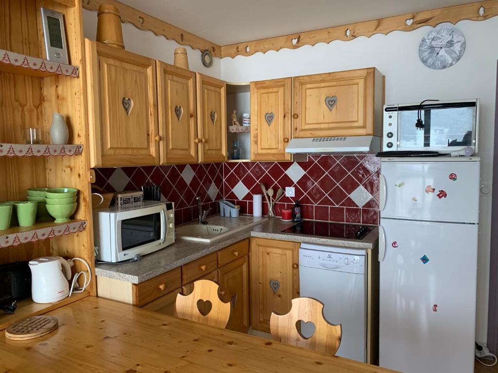 een keuken met houten kasten en een witte koelkast bij La Moucherolle in Villard-de-Lans