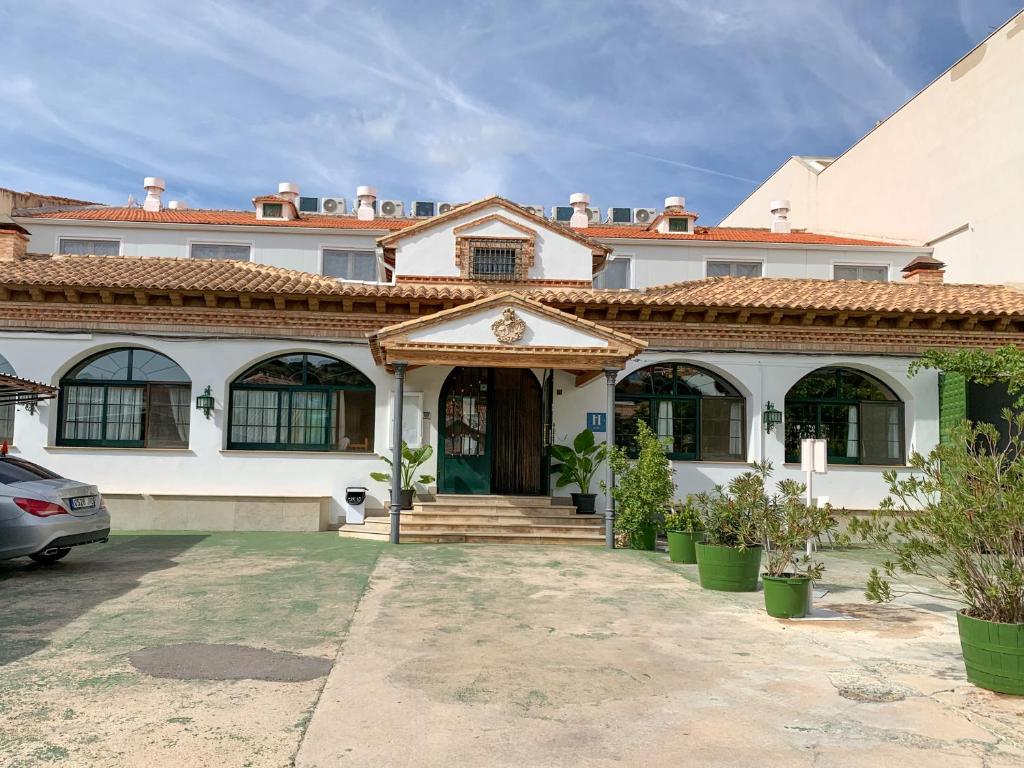 a large white house with a car parked in front of it at Hostal Guadiana in Ruidera