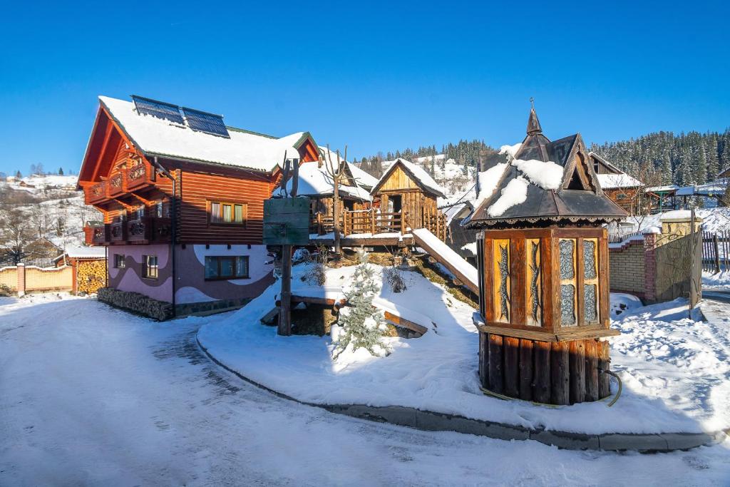 una casa de madera en la nieve con un edificio en Skyta, en Vorokhta