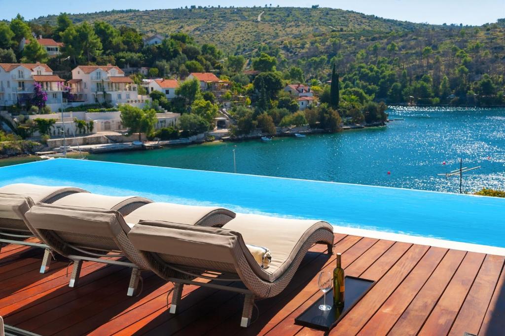 a row of chairs on a deck next to a pool at Luxury Beachfront Villa Blue Star of Brac with private pool at the beach on Brac island - Bobovisca in Bobovišća