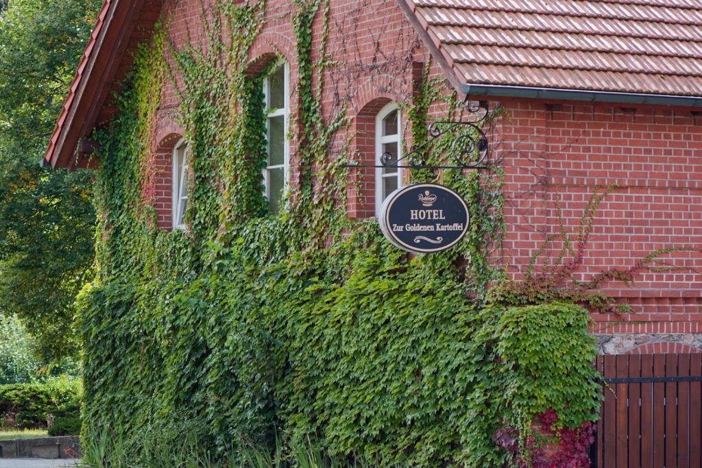 a building covered in ivy with a sign on it at Zur Goldenen Kartoffel in Prötzel