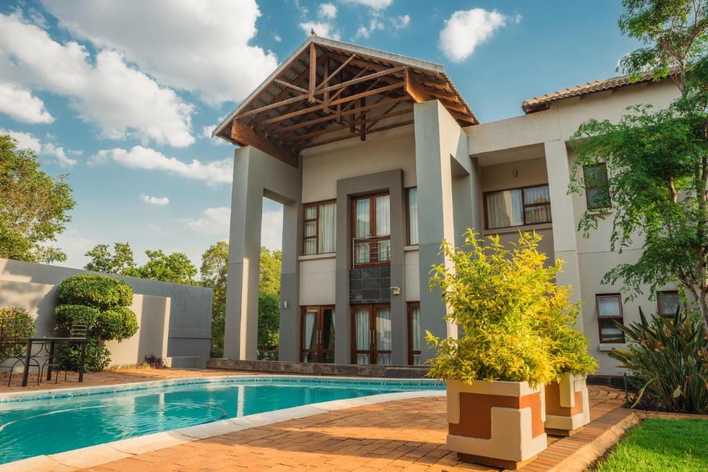 a villa with a swimming pool and a house at Tamboti Guest Lodge in Pretoria