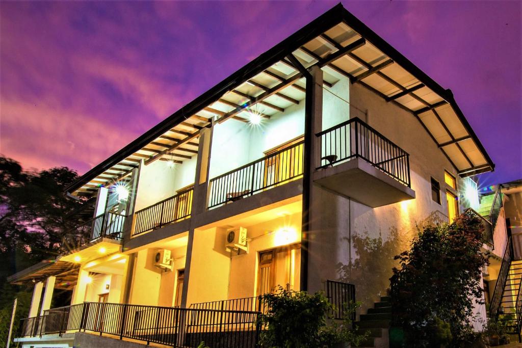 a white building with balconies and a purple sky at Jack Tree Lodge in Kandy