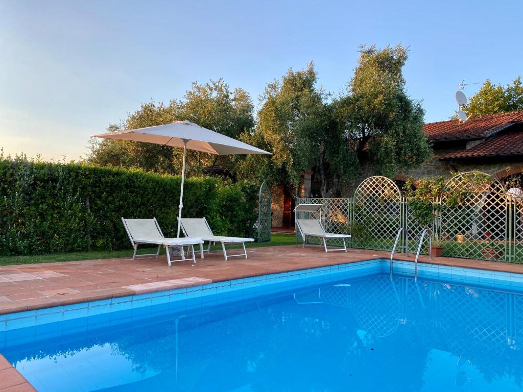 uma piscina com duas cadeiras e um guarda-sol em Perfetta per la Famiglia em Pietrasanta