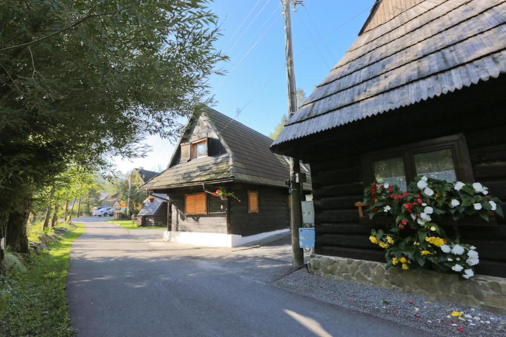 uma casa de madeira com flores ao lado dela em Drevenica pod Lánom em Zuberec