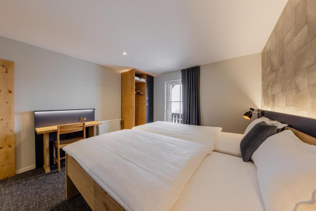 a hotel room with two beds and a desk at Villars Lodge in Villars-sur-Ollon