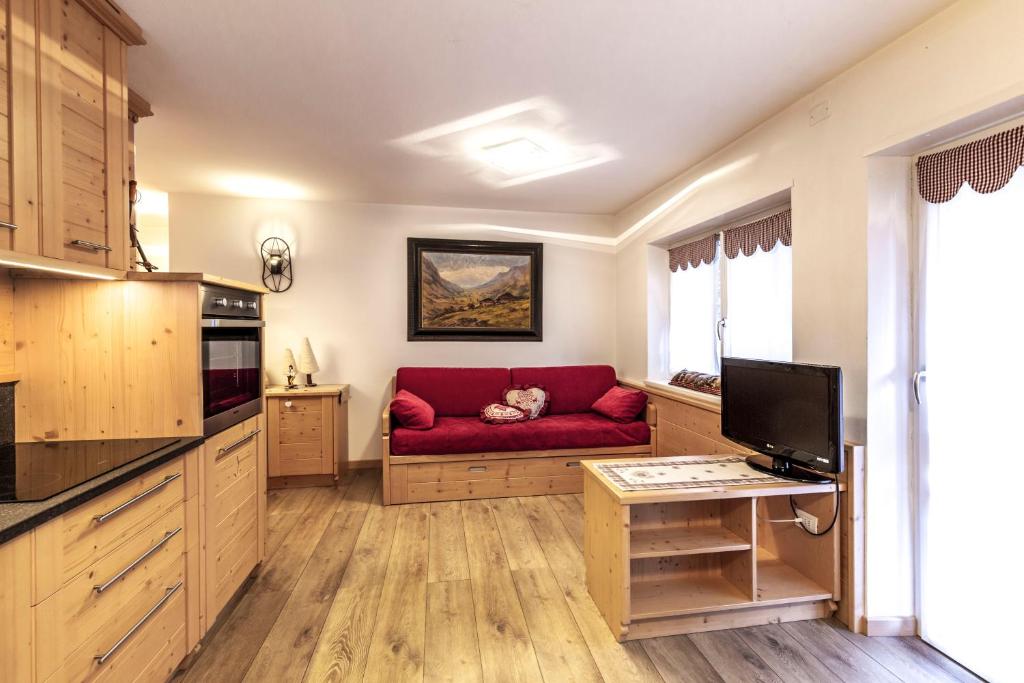 sala de estar con sofá rojo en la cocina en Majon Viva en Campitello di Fassa