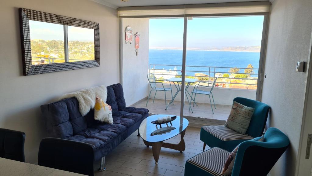 een woonkamer met een bank en stoelen en een balkon bij DEPARTAMENTO EDIFICIO MARES DE MONTEMAR in Concón