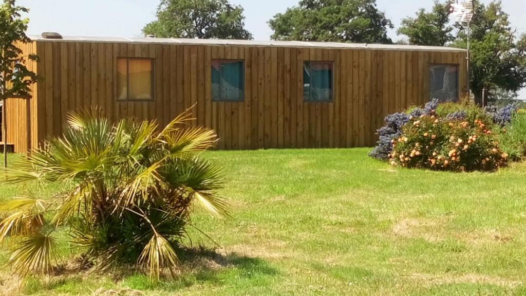 une maison dans une cour avec une pelouse verte dans l'établissement Mobil Home Vintage à la Ferme des buttons, à Rosnay