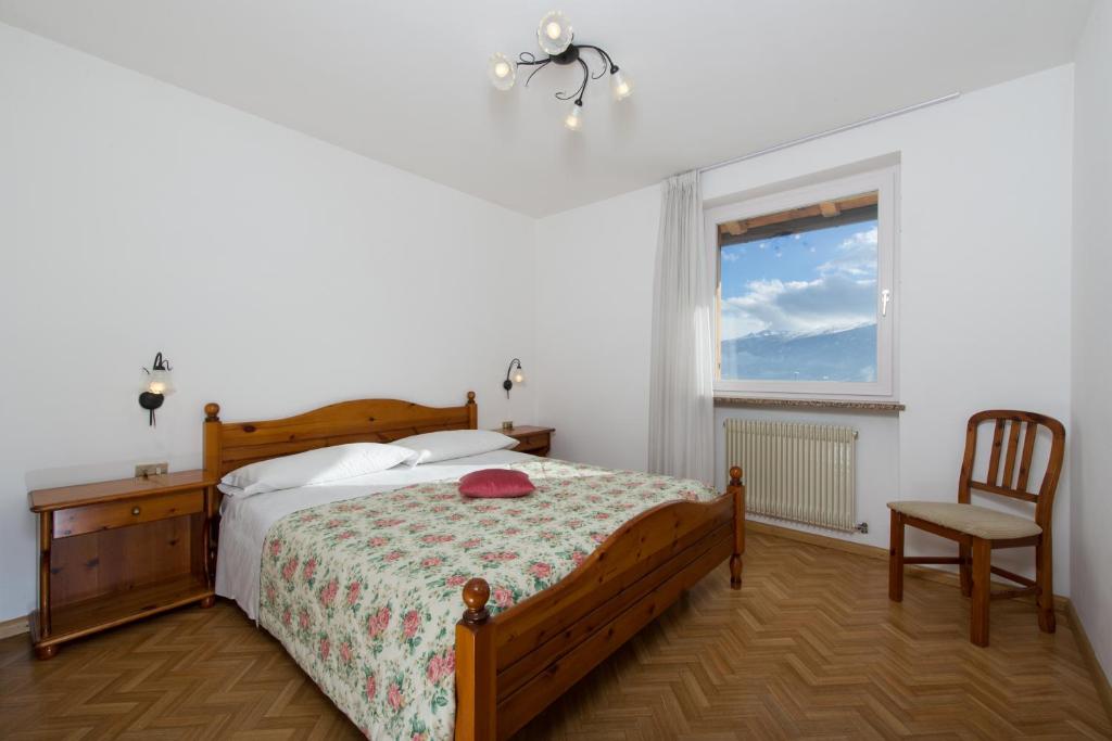 sypialnia z łóżkiem, krzesłem i oknem w obiekcie Residence Villa Boschetto w mieście Carano