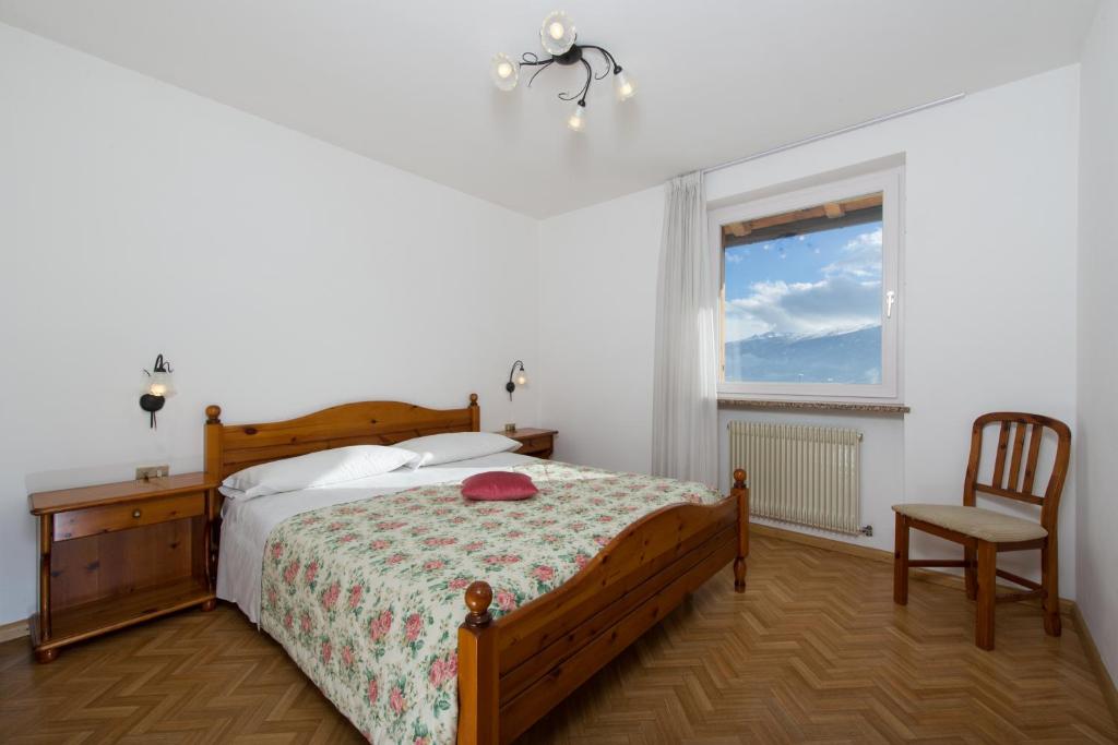 a bedroom with a bed and a chair and a window at Residence Villa Boschetto in Carano