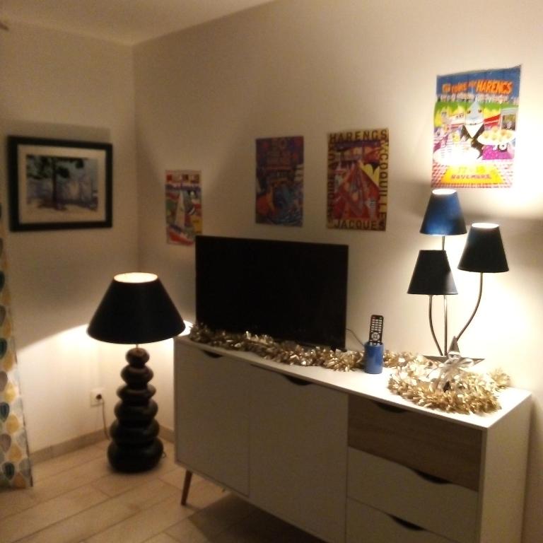 Cette chambre comprend un bureau avec une télévision et deux lampes. dans l'établissement Au galet bleu, à Dieppe