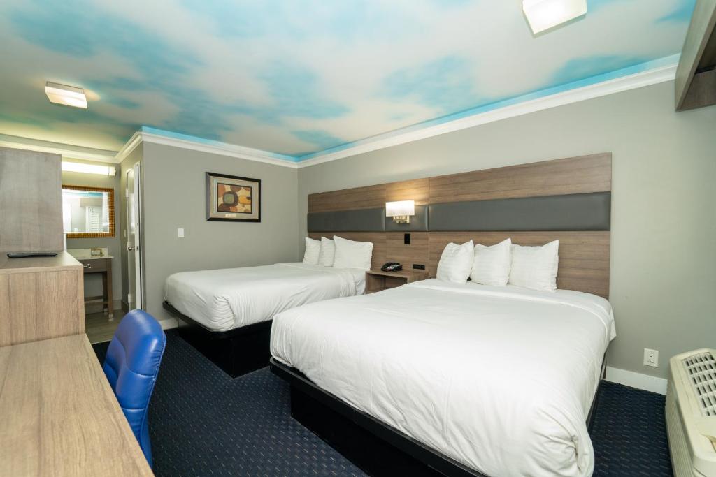 a hotel room with two beds and a television at Hollywood Palms Inns & Suites in Los Angeles