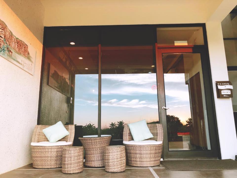 a building with wicker chairs in front of a glass door at Cai Jyu B&B in Magong