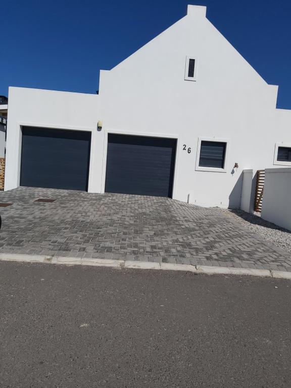 un edificio blanco con tres puertas de garaje. en 26 Sandy Cove, en Hermanus