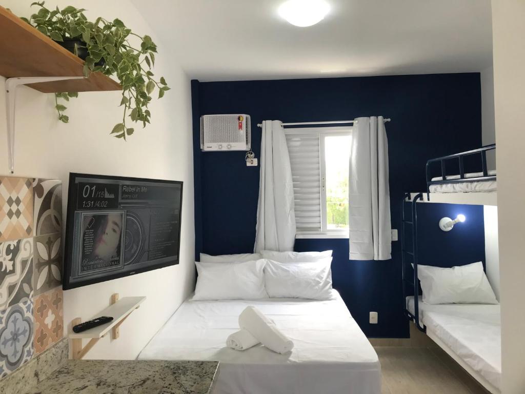 a room with two bunk beds and a tv at Enseada Village Guarujá in Guarujá