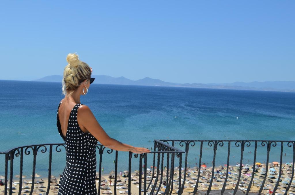 a woman standing on a balcony looking at the beach at Grand Milano Hotel in Ayvalık