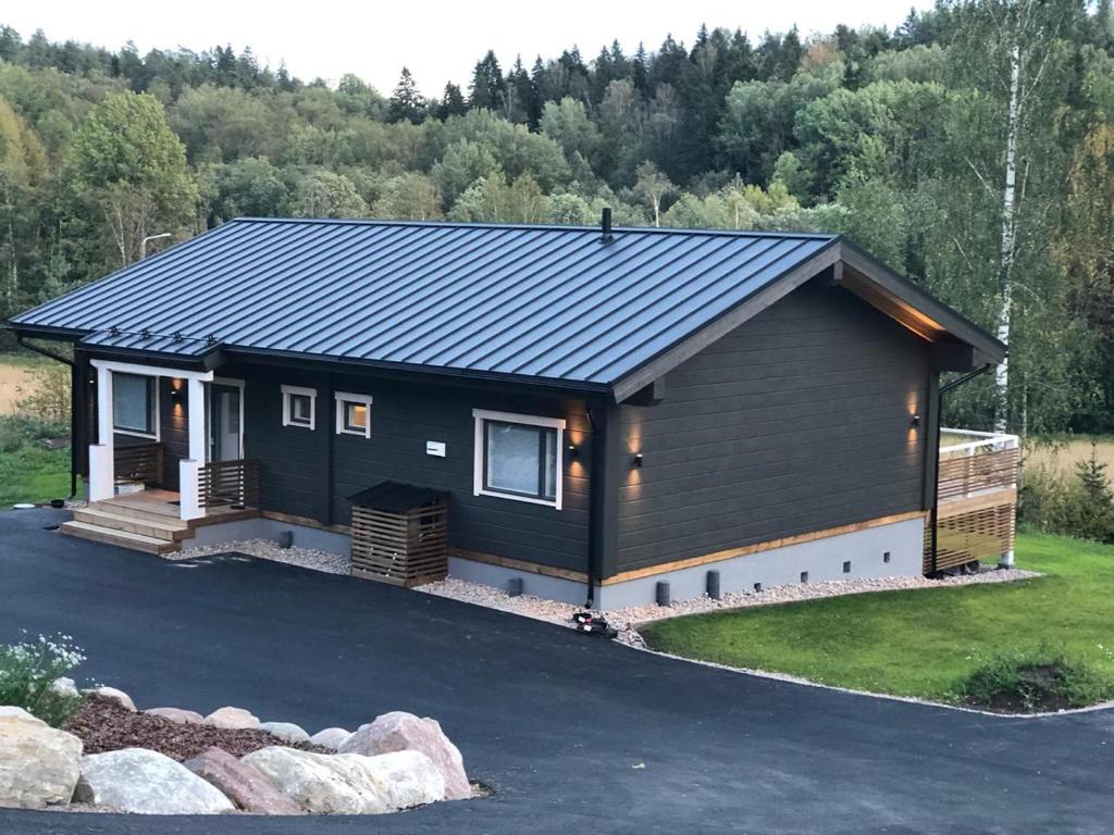 a house with a black roof and a driveway at Villa Kiiski in Teijo