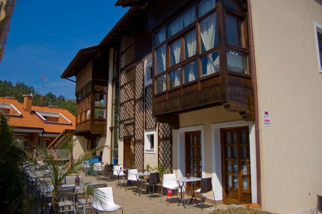 - un bâtiment avec une terrasse dotée de tables et de chaises dans l'établissement Agua Viva Eco H Wellness Castro Urdiales, à Castro Urdiales