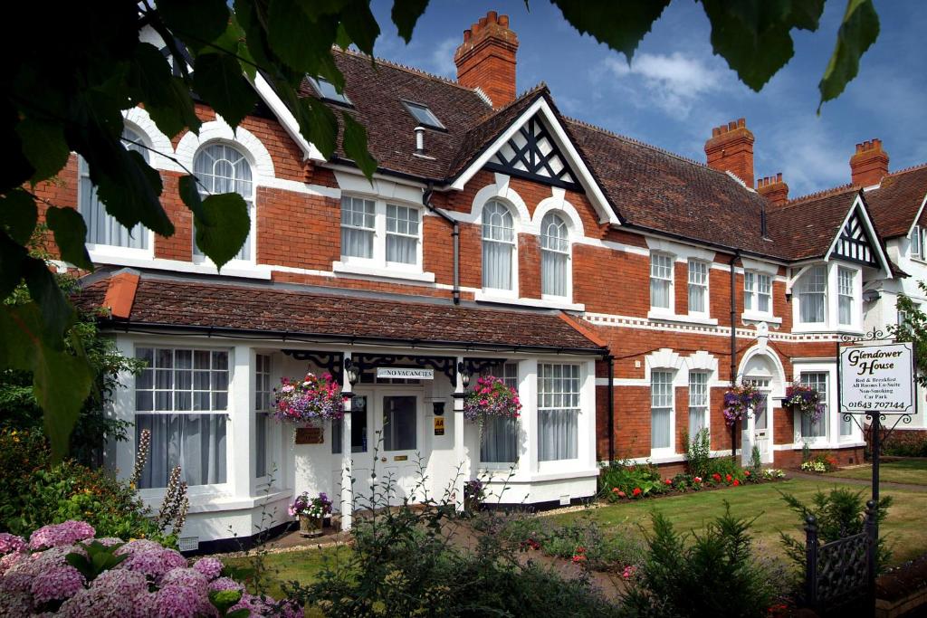 ein rotes Backsteinhaus mit weißen Fenstern und Blumen in der Unterkunft Glendower House in Minehead