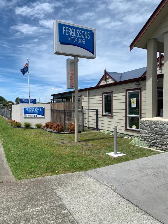 een bord voor een huis met een gebouw bij Fergussons Motor Lodge in  Waipukurau