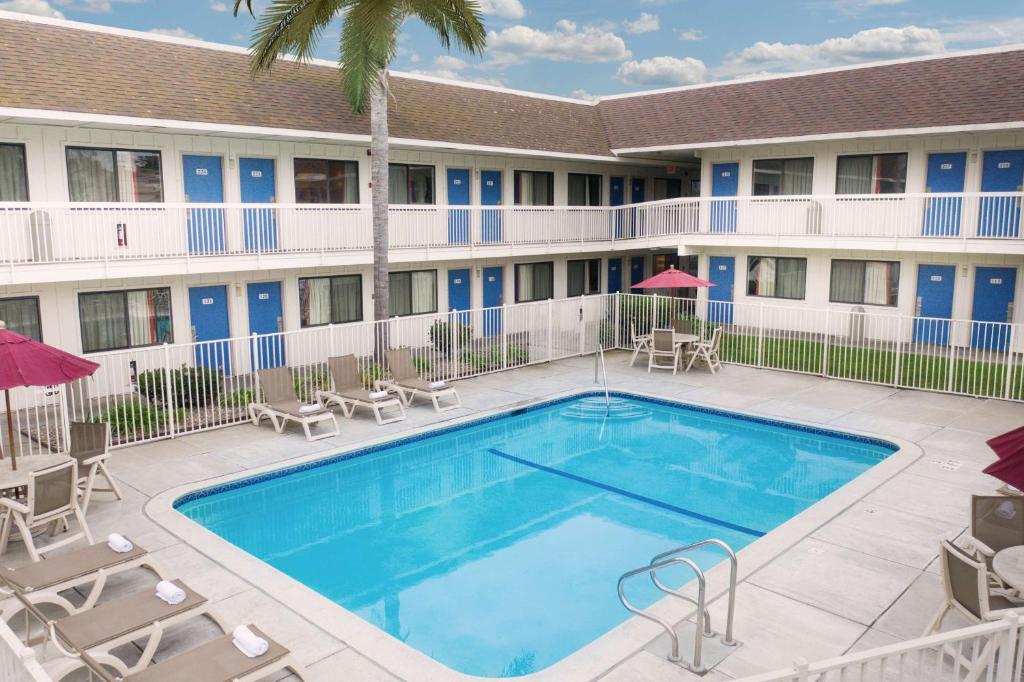 una piscina frente a un hotel con sillas y sombrillas en Motel 6-Pismo Beach, CA, en Pismo Beach