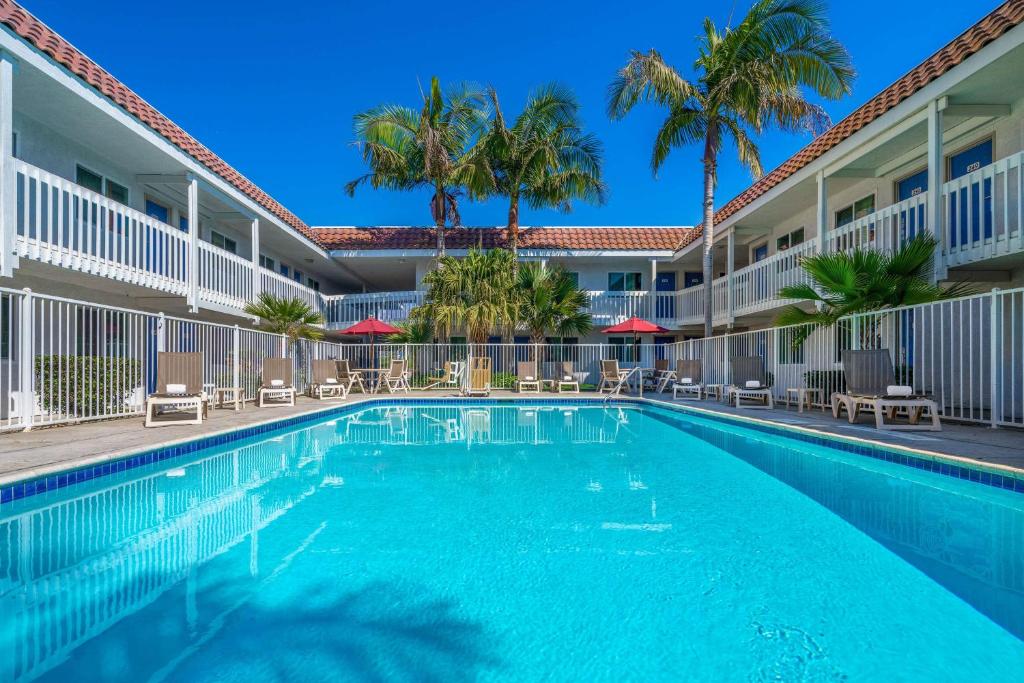 une piscine avec des palmiers en face d'un hôtel dans l'établissement Motel 6-Carpinteria, CA - Santa Barbara - South, à Carpinteria