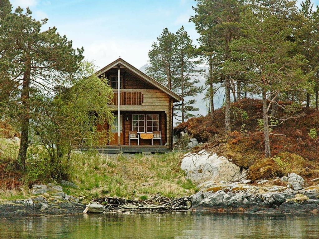 a house on a hill next to a body of water at 5 person holiday home in VÅGLAND in Bårdset