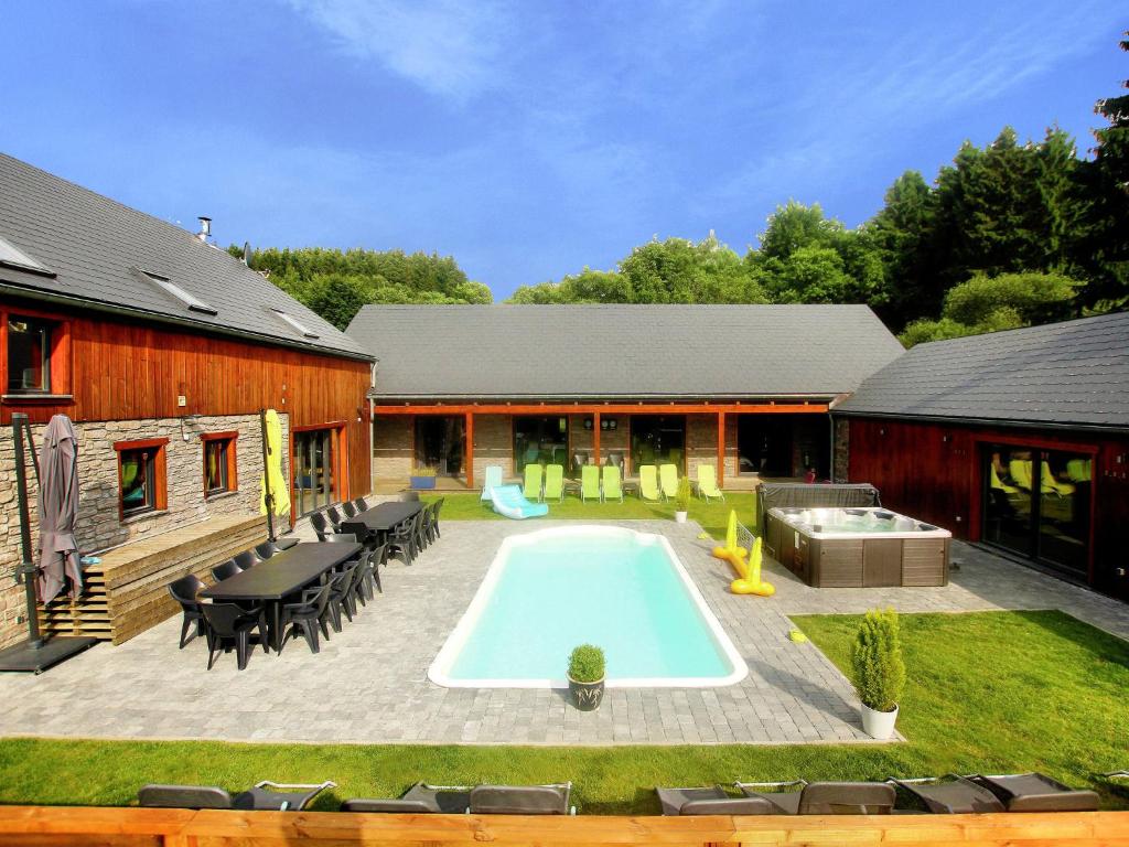 a backyard with a swimming pool next to a house at Villa with heated outdoor pool and sauna in Manhay