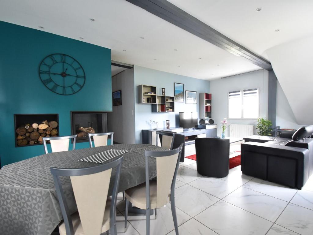 une salle à manger avec une table, des chaises et une horloge dans l'établissement Modern house with private terrace, à Quinéville