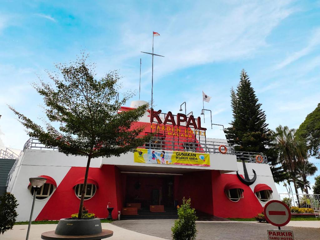 a red and white building with a sign on it at Kapal Garden Hotel Malang in Malang