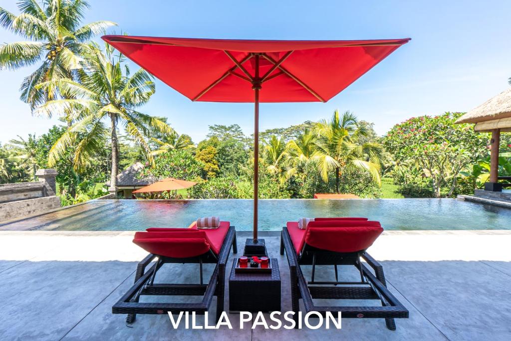 a red umbrella and chairs next to a pool at Rouge - Private Villa Passion in Ubud