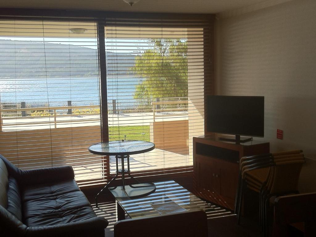 sala de estar con una gran ventana con mesa y TV en Departamento Lago Vichuquen, en Lago Vichuquen