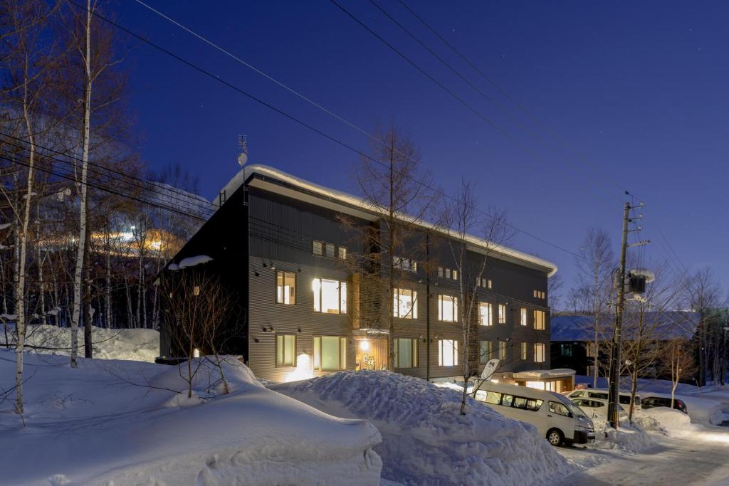 un bâtiment dans la neige avec une voiture devant dans l'établissement SnowDog Village, à Niseko