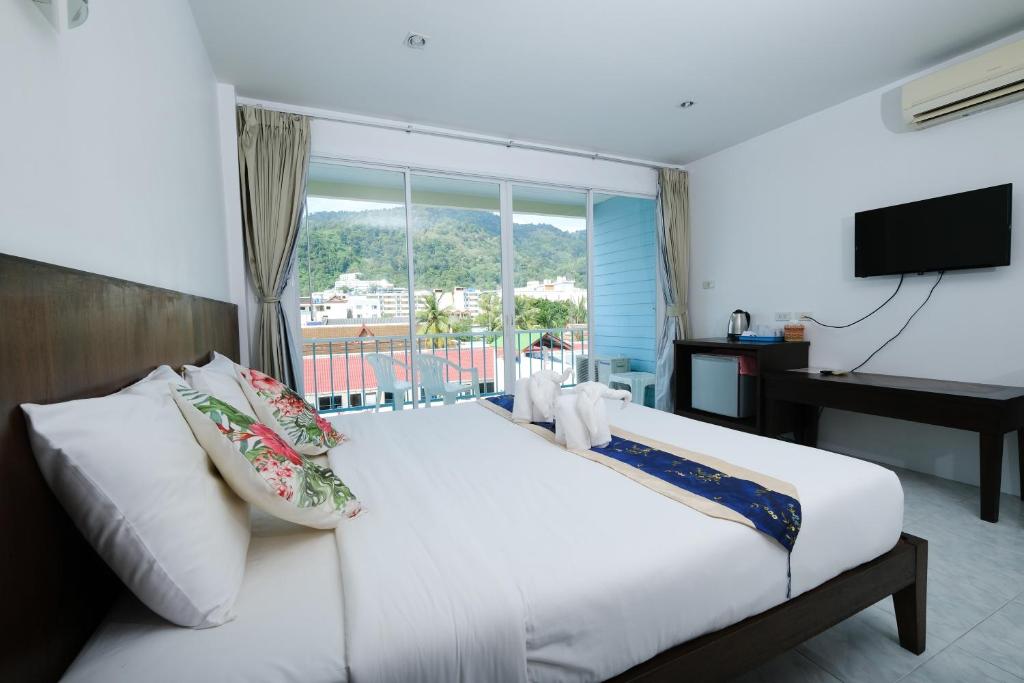 a bedroom with a large white bed with a window at Kiwi Boutique Hotel in Patong Beach