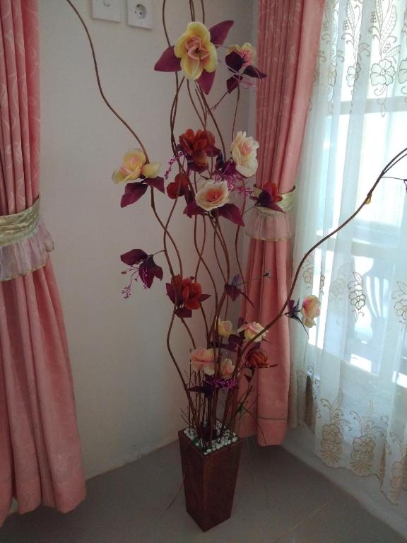 a bouquet of flowers in a vase next to a window at Homestay Anggur in Bukittinggi