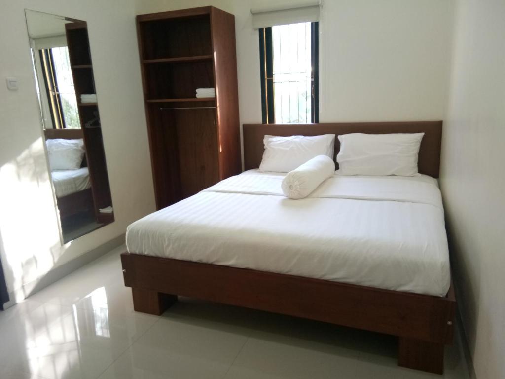 um quarto com uma cama com lençóis brancos e almofadas em Clean & Comfort Homestay em Ambon