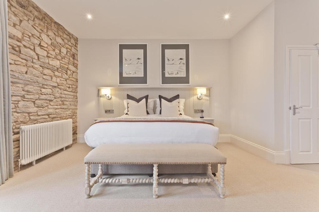 a bedroom with a large bed and a stone wall at Tithe Barn - Self Check In Hotel in Cockermouth